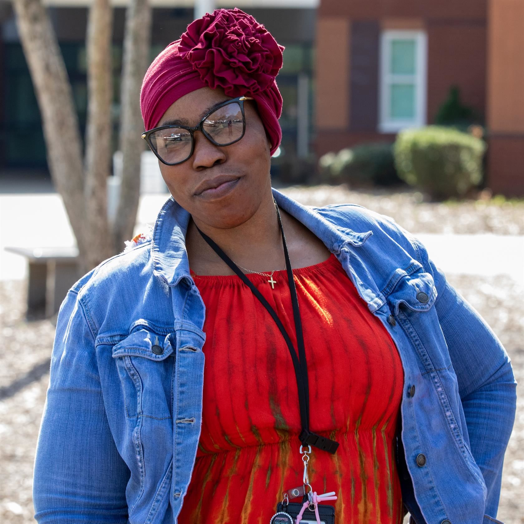 Staff member smiles while standing in front of school.